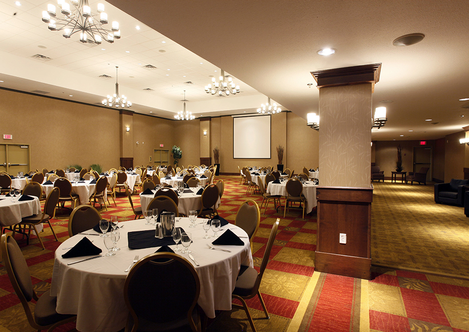 A banquet table set with flowers, wine glasses, and napkins in an upscale room for events. The Marie Pomeroy room at the Pomeroy Hotel & Conference Centre - Fort St. John in Alberta, Canada can be used to host upscale events, weddings, banquets, corporate events, and more.