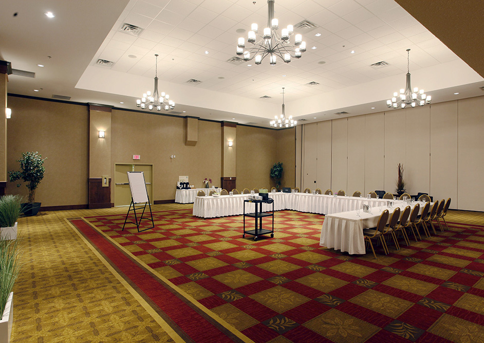 A banquet table set with flowers, wine glasses, and napkins in an upscale room for events. The Scotty Pomeroy room at the Pomeroy Hotel & Conference Centre - Fort St. John in Alberta, Canada can be used to host upscale events, weddings, banquets, corporate events, and more.