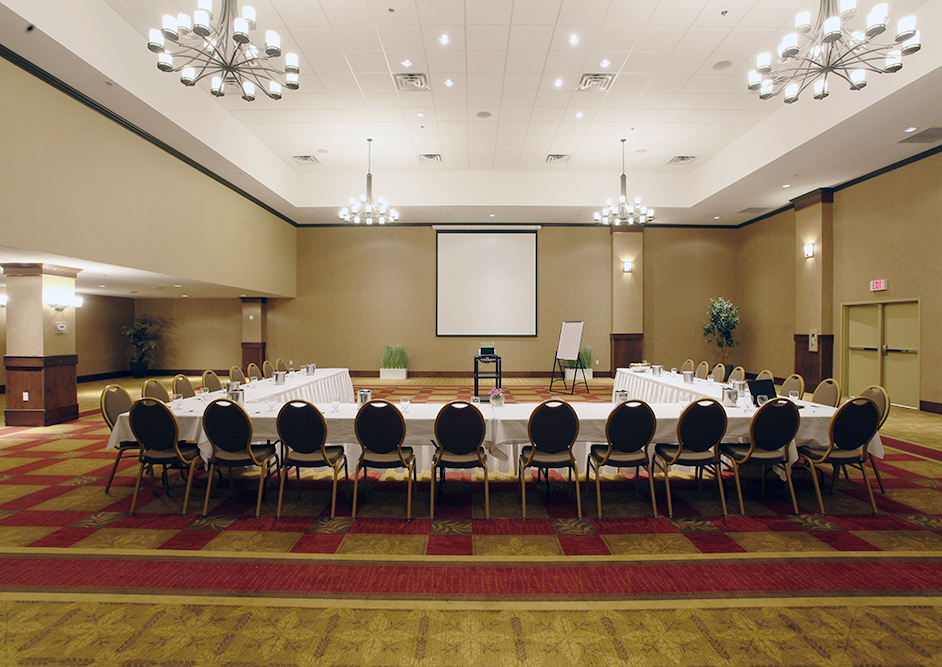 A banquet table set with flowers, wine glasses, and napkins in an upscale room for events. The Scotty Pomeroy room at the Pomeroy Hotel & Conference Centre - Fort St. John in Alberta, Canada can be used to host upscale events, weddings, banquets, corporate events, and more.