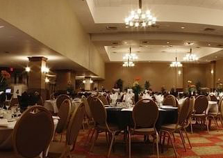 Banquet tables set with flowers, wine glasses, and napkins in an upscale room for events. The Ralph Pomeroy Ballroom at the Pomeroy Hotel & Conference Centre - Fort St. John in Alberta, Canada can be used to host upscale events, weddings, banquets, corporate events, and more.