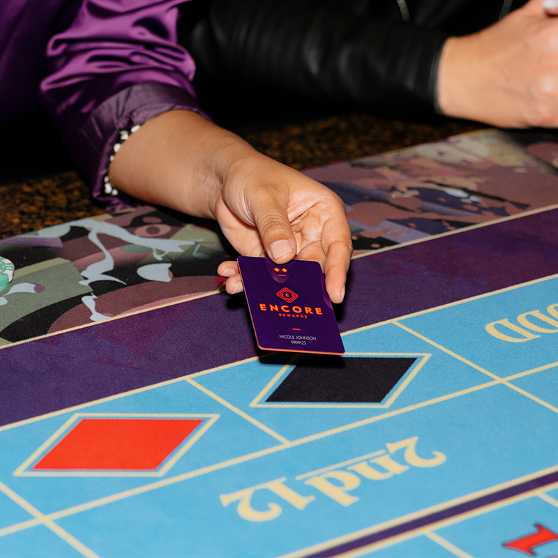 Close up of woman's hand holding Encore Rewards card while playing roulette